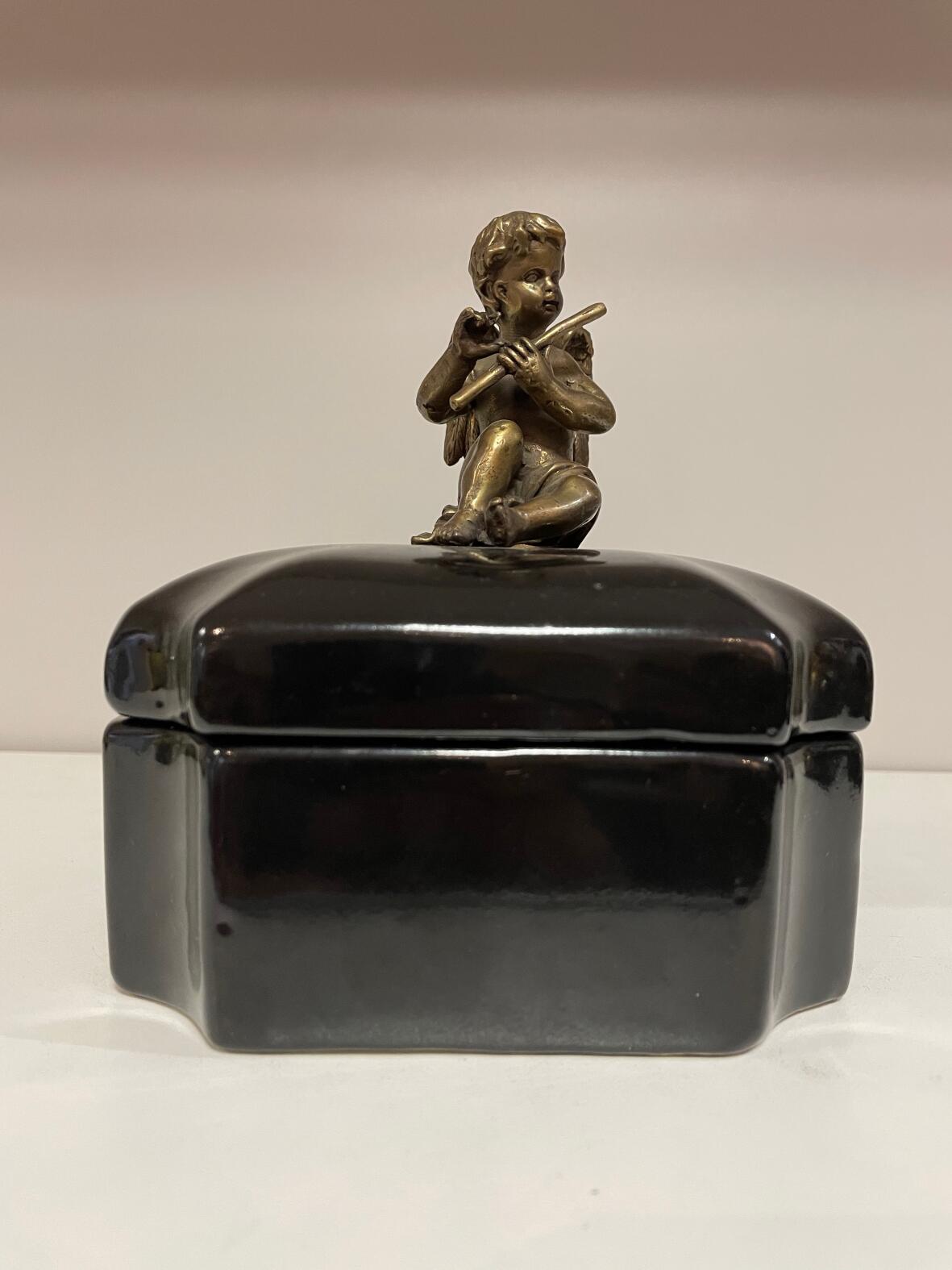 Schwarze Deckeldose mit Bronzestatuette eines Engels als Griff